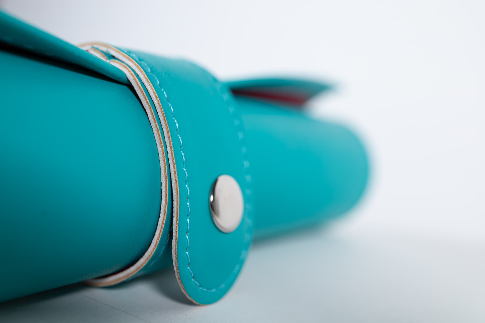 Close-up of the turquoise leather case, stitching, and snap closure